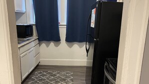 Een compacte keuken met een magnetron, koelkast en een blauwe waterdispenser.