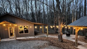 A cabin with a covered patio, a deck, and string lights.