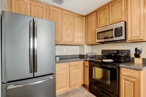 Fully equipped kitchen with a refrigerator, stove, microwave, and toaster.