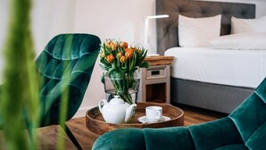 Une chambre d’hôtel avec un lit, une table de chevet et un plateau contenant une théière et une tasse.
