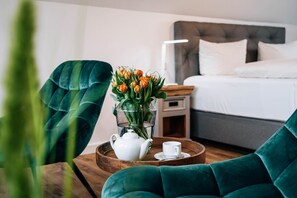 Een hotelkamer met een bed, nachtkastje en een dienblad met theepot en kopje.