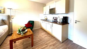 A compact hotel room with a kitchenette, a dining area with a table and chairs, and a bed. - Vacation apartment Mare Nostrum 6 - close to the beach, close to the city, close to relaxation, in short - (Sylt)