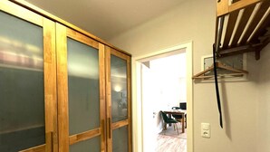 A hallway with a wooden wardrobe, a coat rack, and a dining area in the background. - Vacation apartment Mare Nostrum 6 - close to the beach, close to the city, close to relaxation, in short - (Sylt)