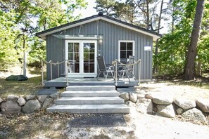 A small, single-story building with a porch, stone steps, and a sign indicating the number 72.