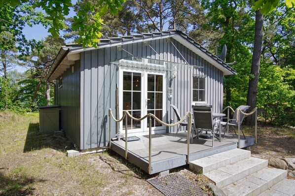 A small wooden cabin with a porch, a door, and a window.
