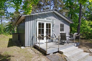 A small wooden cabin with a porch, a door, and a window.