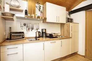 Una cocina moderna con armarios blancos, un tostador, una cafetera y un microondas.