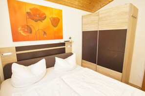 A bedroom with a bed, a headboard, a wardrobe, and a painting on the wall.