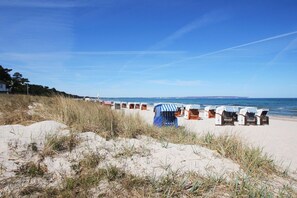Una playa con hileras de cabañas de playa y una duna arenosa al frente.