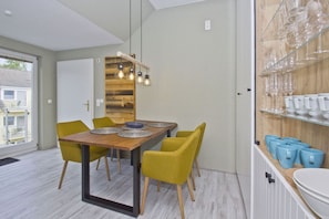 A dining area with a wooden table, yellow chairs, and a modern pendant light. - Just 100 m from the beach, apartment with a balcony and private sauna - Apt. Eldena Vacation Rental 09 - (Middelhagen)