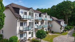 A multi-story residential building with balconies, a paved driveway, and surrounding greenery. - Only 100 m to the beach, apartment with balcony and terrace - App. Eldena apartment 19 - (Middelhagen)