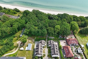 An aerial view of a residential area with a beach, dense greenery, and multiple houses. - Just 100 m from the beach, apartment with a balcony and terrace - Apt. Eldena Apartment 19 - (Middelhagen)