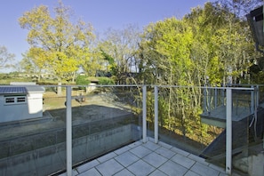 A balcony with a view of trees and a building in the background. - Just 100 m from the beach, apartment with a balcony and terrace - Apt. Eldena Apartment 19 - (Middelhagen)