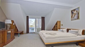 A bedroom with a bed, a television, a desk, and a painting on the wall. - Only 100 m to the beach, apartment with balcony and terrace - App. Eldena apartment 19 - (Middelhagen)
