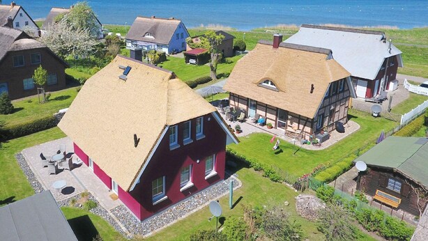 Un borgo costiero con case tradizionali, vista libera sul mare e un giardino curato.