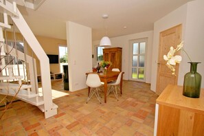 A spacious dining area with a wooden table and chairs, a white ceiling light, and a wooden door.