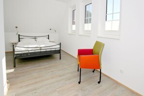 A bedroom with a bed, a chair, and a window. - Falke Vacation Home - a stylish vacation home with a view of the sea, a terrace, and a fireplace - (Gager)