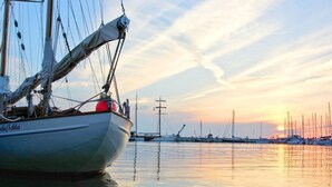 Una barca a vela ormeggiata in una marina, con acque calme e un tramonto sullo sfondo.