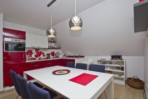 A modern kitchen with red cabinets, a white countertop, and two pendant lights. - Vacation apartment close to the beach with a beautiful garden - Ferienhaus Gisela - Holiday home (Putbus)