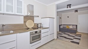 A modern kitchen with white cabinets, a wooden countertop, and a built-in oven. - Quiet location close to the sea, terrace and garden - Ferienhaus Auszeit FeWo 01 - (Middelhagen)