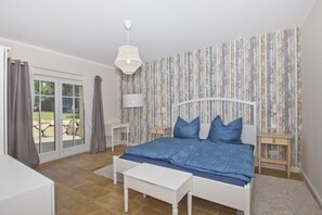 A bedroom with a bed, a desk, a chair, a lamp, and a view of the outdoors. - Quiet location near the sea, with a patio and garden - Ferienhaus Auszeit FeWo 01 - (Middelhagen)