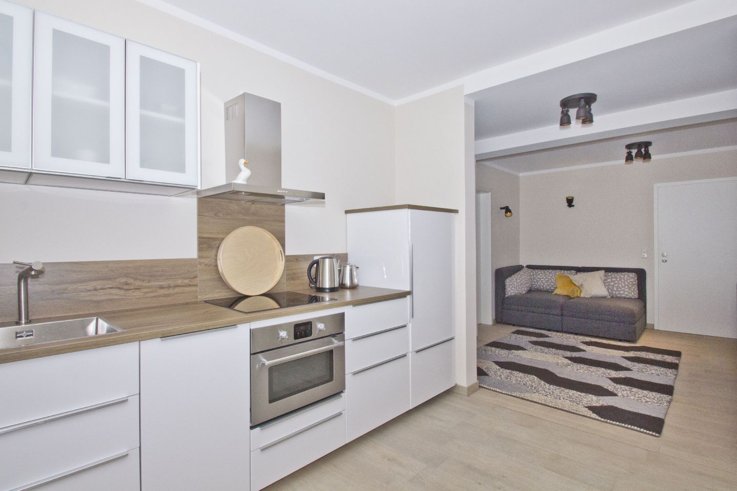 Una cucina moderna con mobili bianchi, un piano di lavoro in legno e un forno integrato.