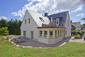 A modern house with a large patio, a covered outdoor seating area, and a well-maintained garden.