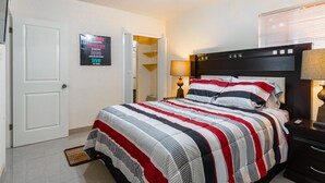 Een netjes ingerichte slaapkamer met een bed, bedlampje en een deur naar een andere kamer.