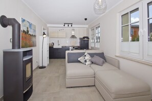 Eine moderne Küche mit Einbauherd, ein Essbereich mit einer Couch und ein großes Fenster mit Jalousien.