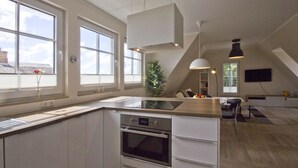 Una cocina moderna con una isla central, ventanas amplias y un comedor adyacente.