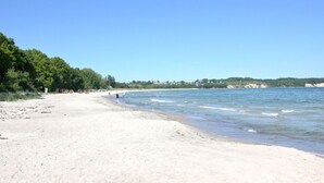 Una playa con arena, agua tranquila y cielo despejado.