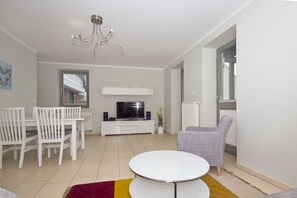 Una sala moderna con comedor, televisor de pantalla plana y candelabro.