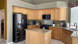 Una cocina con armarios de madera, un refrigerador, un microondas, una estufa y un lavaplatos.