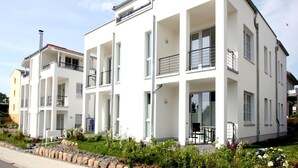 Ein modernes Mehrfamilienhaus mit Balkonen, großen Fenstern und einem gepflegten Garten.
