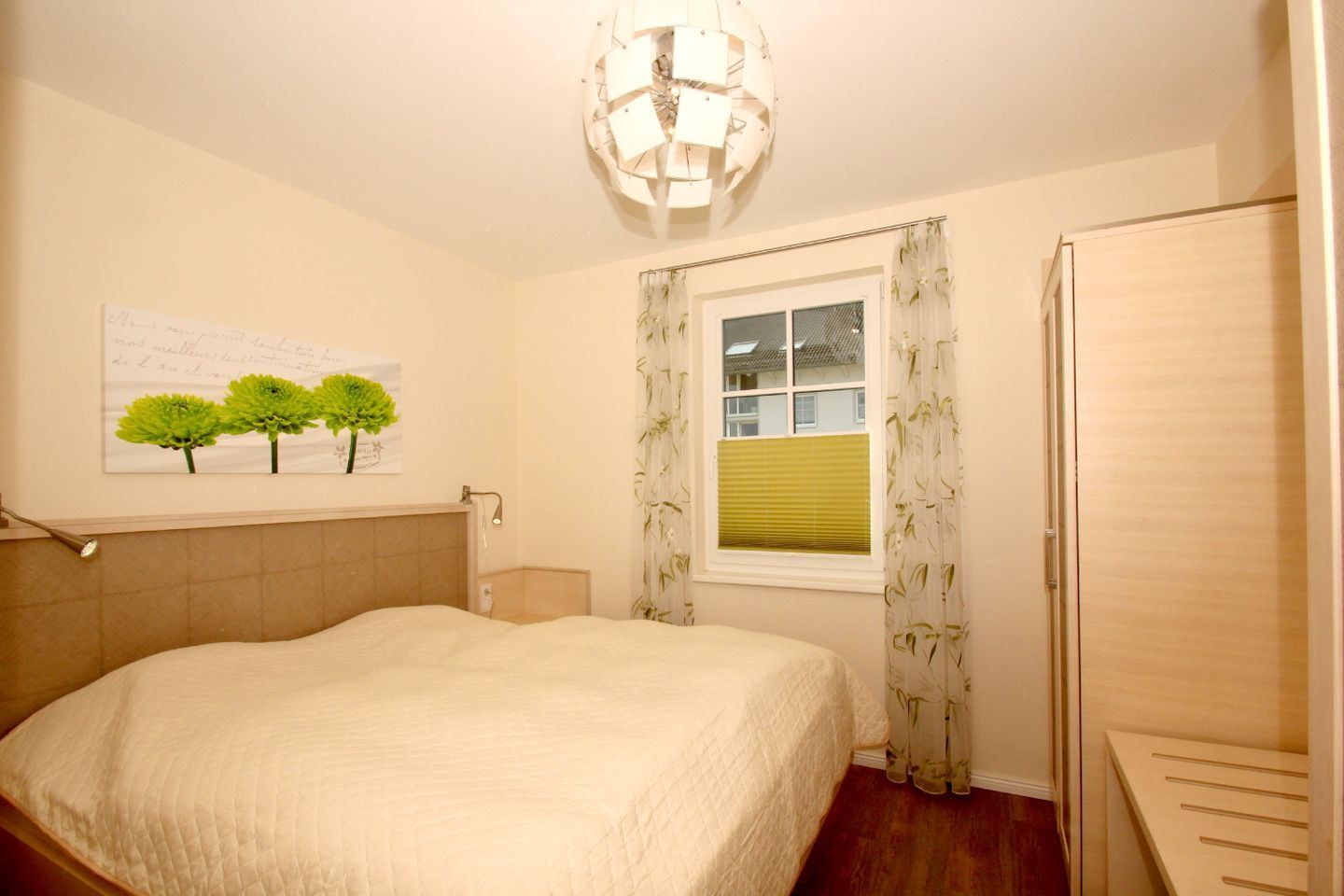 Un dormitorio con cama, ventana con cortinas, lámpara de pared y una puerta.