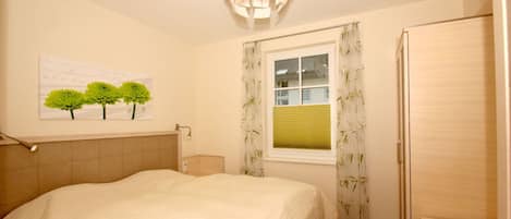 Un dormitorio con cama, ventana con cortinas, lámpara de pared y una puerta.