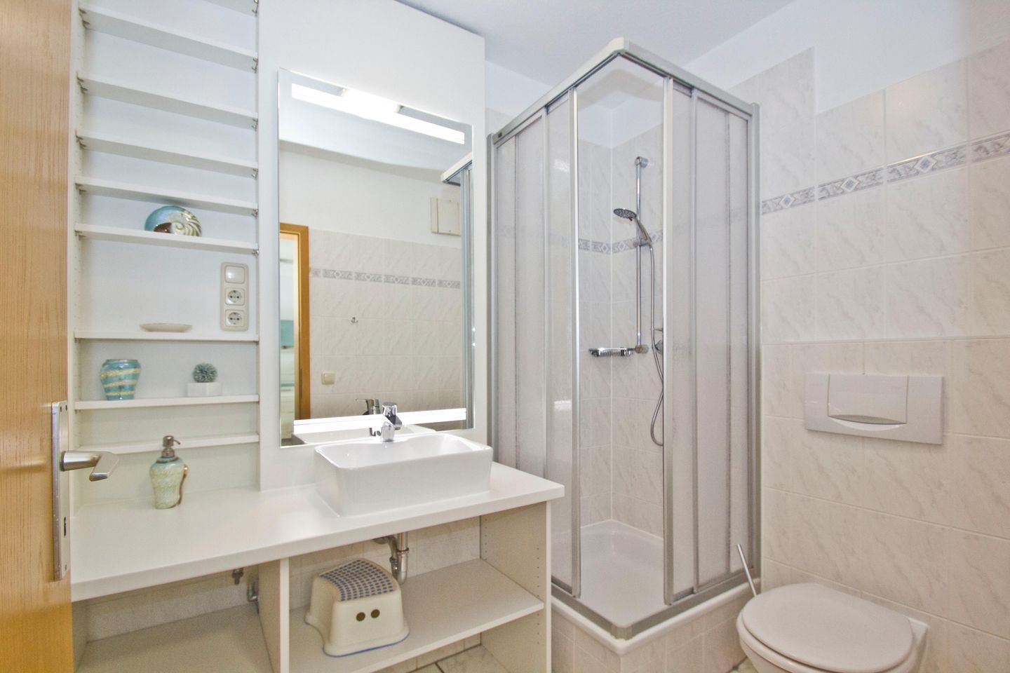 Une salle de bain avec une douche à parois de verre, un lavabo blanc et des toilettes.