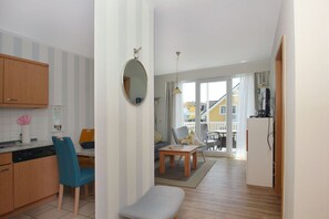 A compact living space with a kitchenette, a dining area, and a seating area with a view to the outside. - Balcony, free use of the AHOI adventure pool and sauna - Villa Karola FeWo 12 - (Göhren)