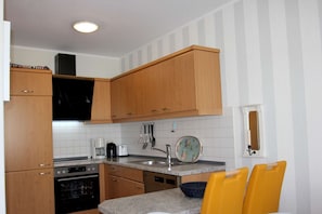 A compact kitchen with wooden cabinets, a built-in oven, a coffee maker, and a toaster.