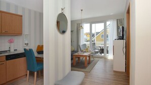 A compact living space with a kitchenette, a dining area, and a seating area with a view to the outside. - Balcony, free use of the AHOI adventure pool and sauna - Villa Karola FeWo 12 - (Göhren)