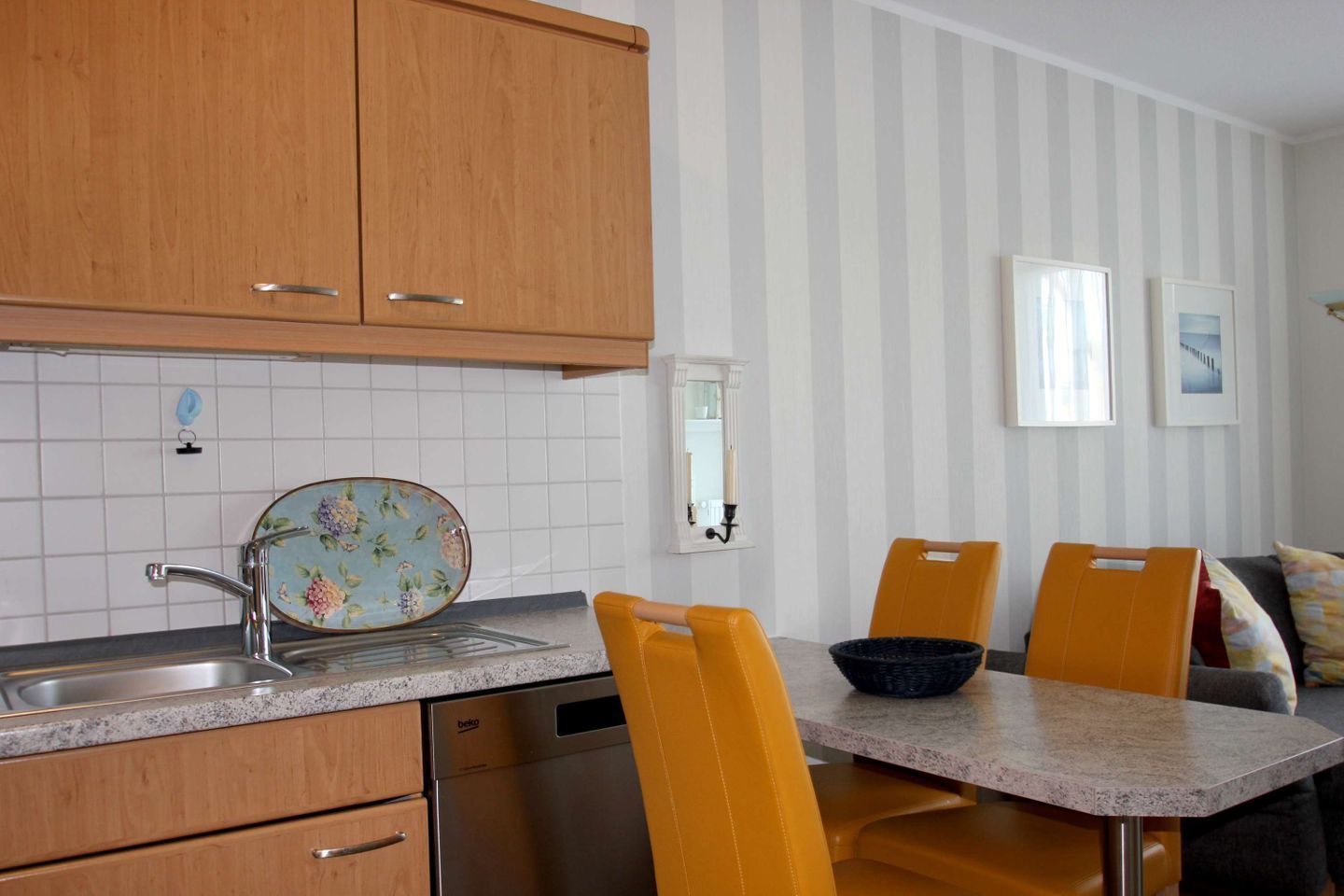 A kitchen with wooden cabinets, a sink, and a dining area with a table and chairs.