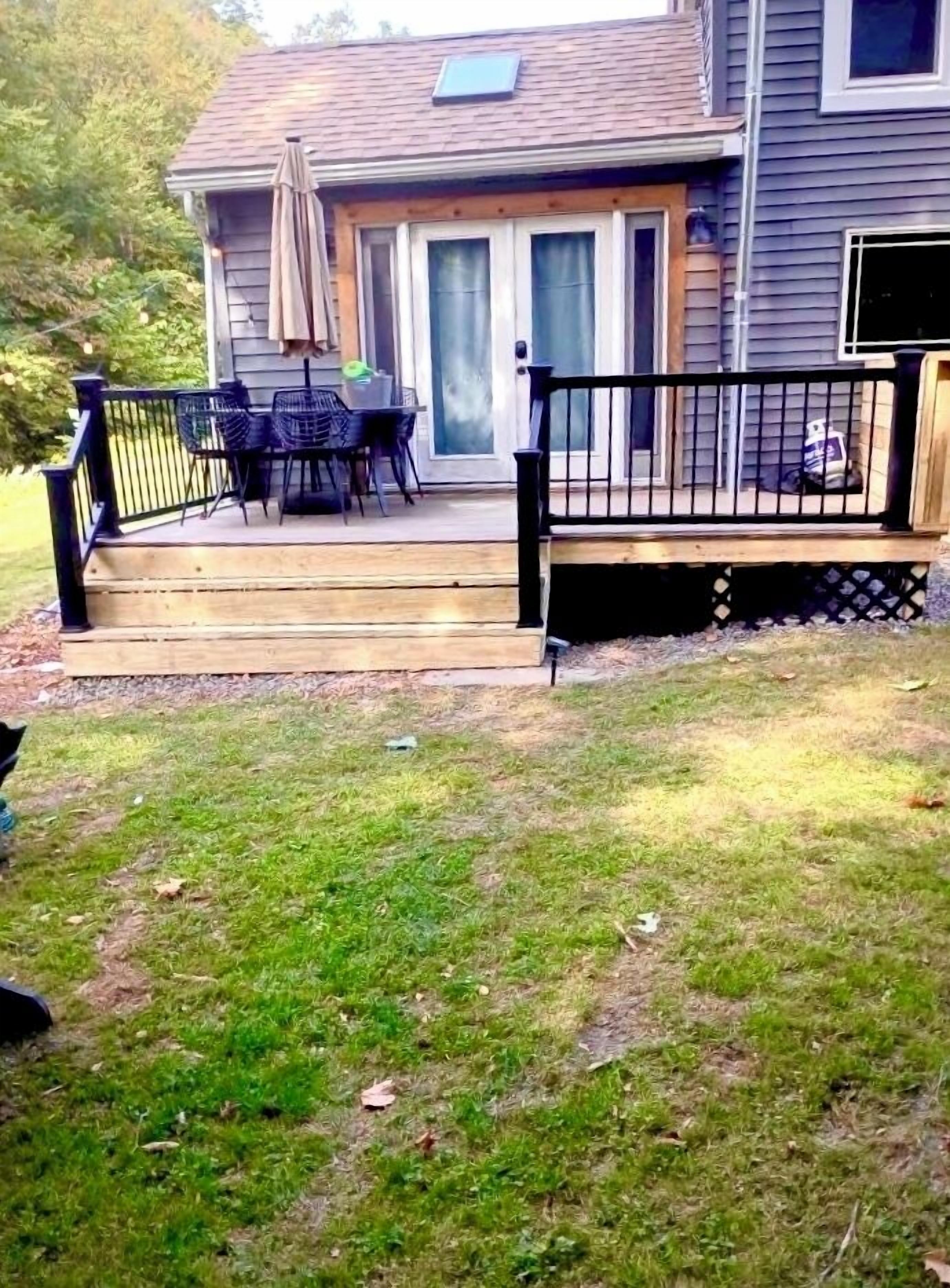 Uma casa com varanda, móveis de exterior e um gramado.