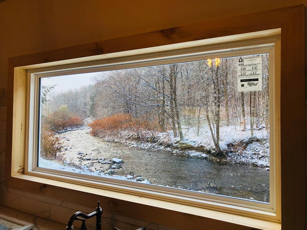 A window with a view of a snowy landscape, including a river and trees.