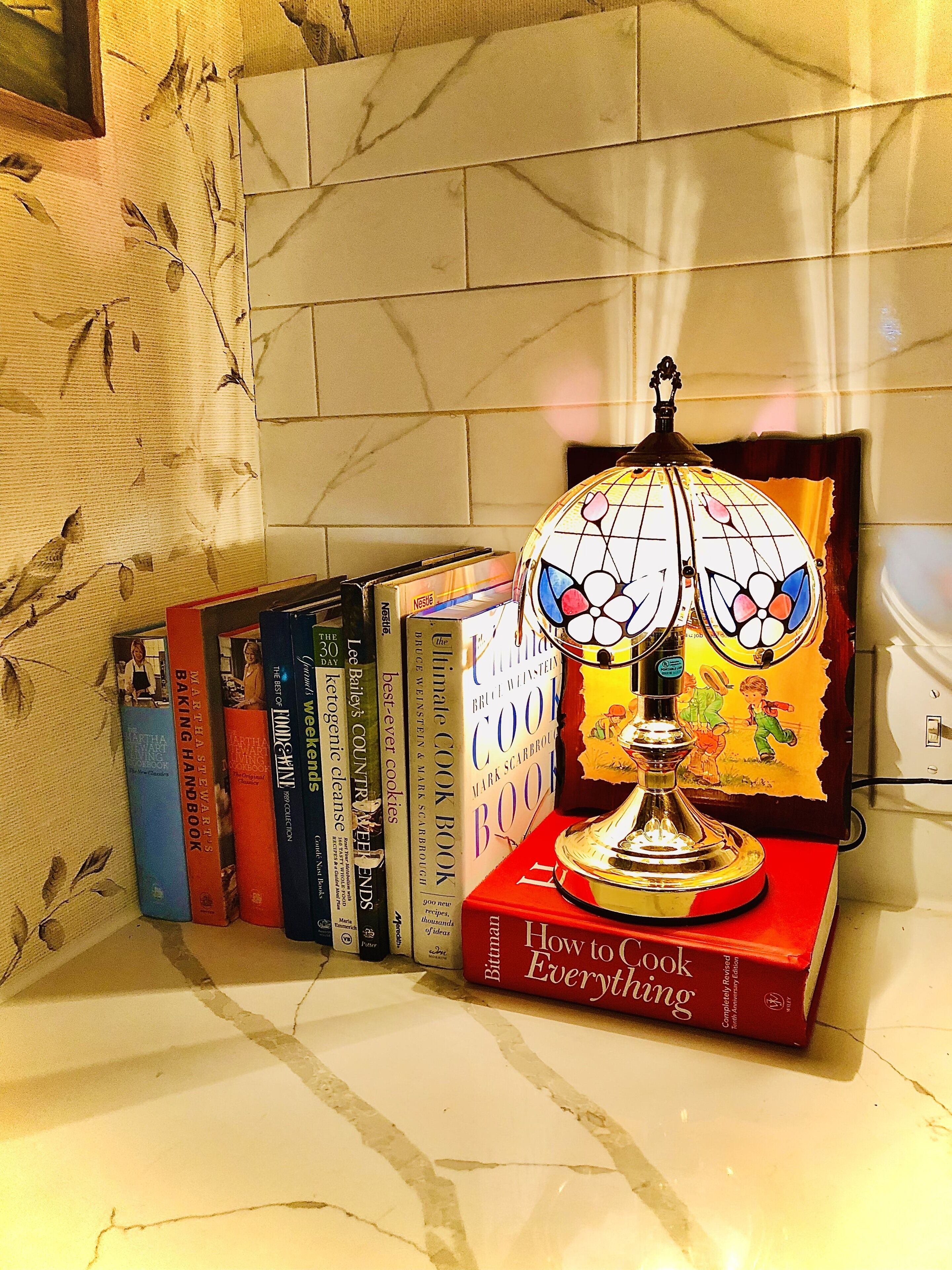 Een boekenplank met kookboeken en een decoratieve lamp.