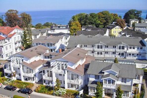 A coastal residential area with multi-story houses featuring balconies and a view of the sea.