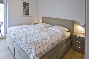 A modern bedroom with a large bed, a bedside table, and a nightstand.