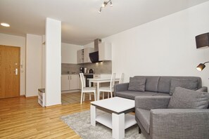 Ein modernes Wohnzimmer mit einem grauen Sofa, einem weißen Couchtisch und einem Essbereich mit einem weißen Tisch und Stühlen.
