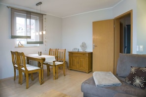 Una sala de estar acogedora con comedor, muebles de madera y un sofá gris con cojines decorativos.