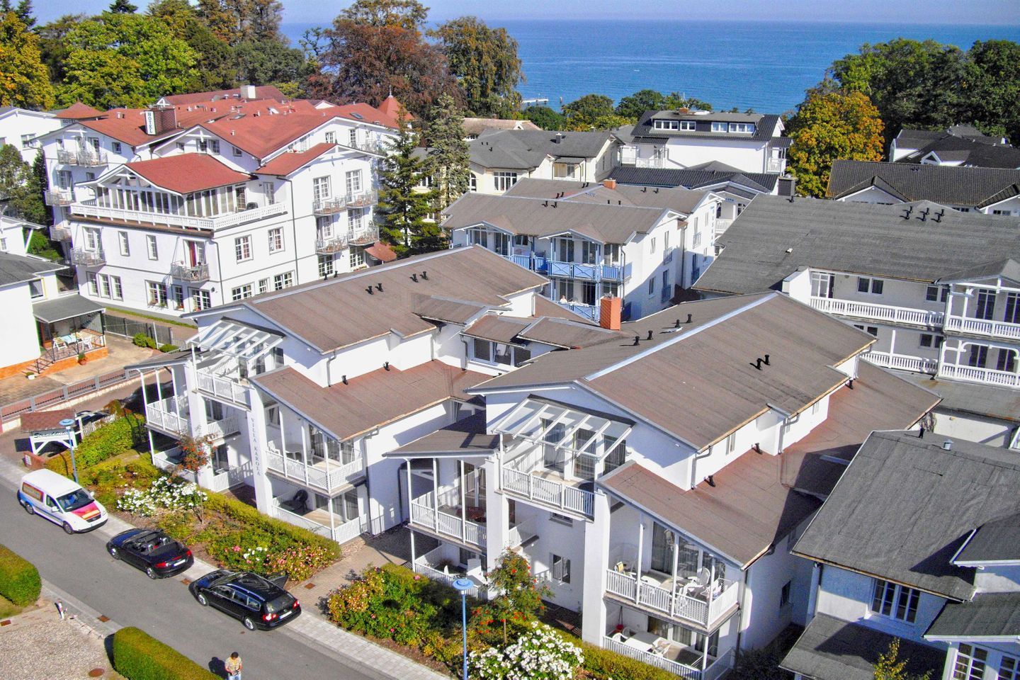 A coastal residential area with multi-story houses, some with balconies, and a view of the sea.