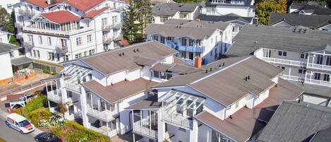 A coastal residential area with multi-story houses, some with balconies, and a view of the sea.